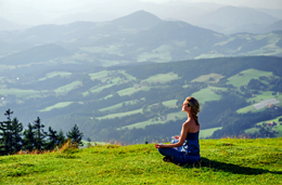 Meditationshaltungen - Eine Frau meditiert auf einer Wiese