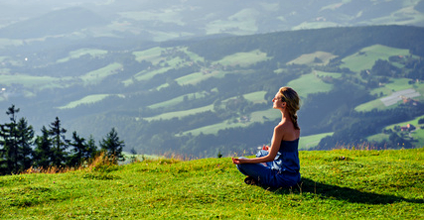 Meditationshaltungen - Eine Frau meditiert auf einer Wiese